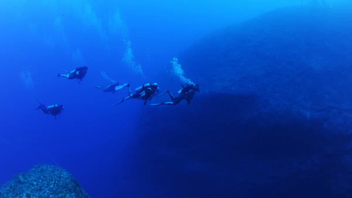 Divers underwater in deep blue ocean